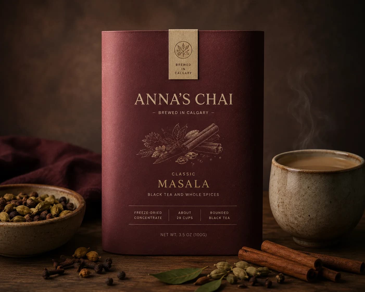 Anna's Classic Masala package beside cardamom, cinnamon, and a cup of chai